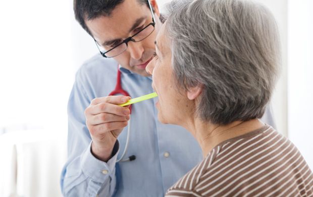 Arzt untersucht Zunge von Patientin