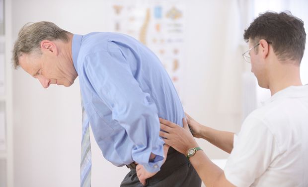 Arzt untersucht Patienten mit Rückenschmerzen Arzt untersucht Patienten mit Rückenschmerzen