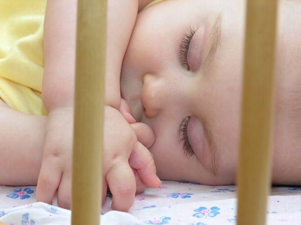 Schlafendes Baby im Gitterbett